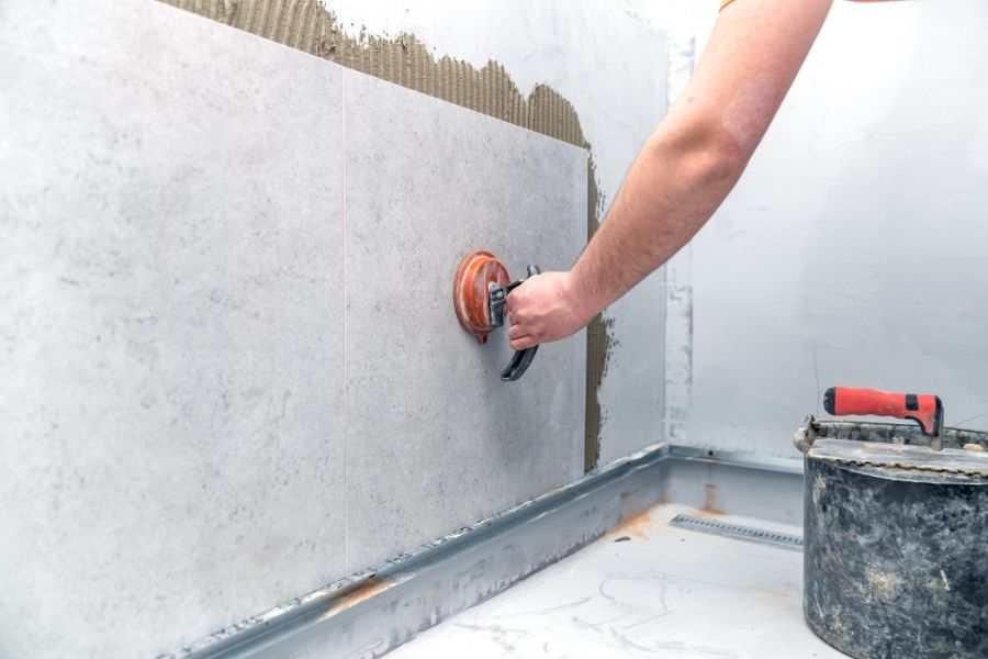 Pose de carrelage grand format sur mur avec application d'adhésif et calcul des joints