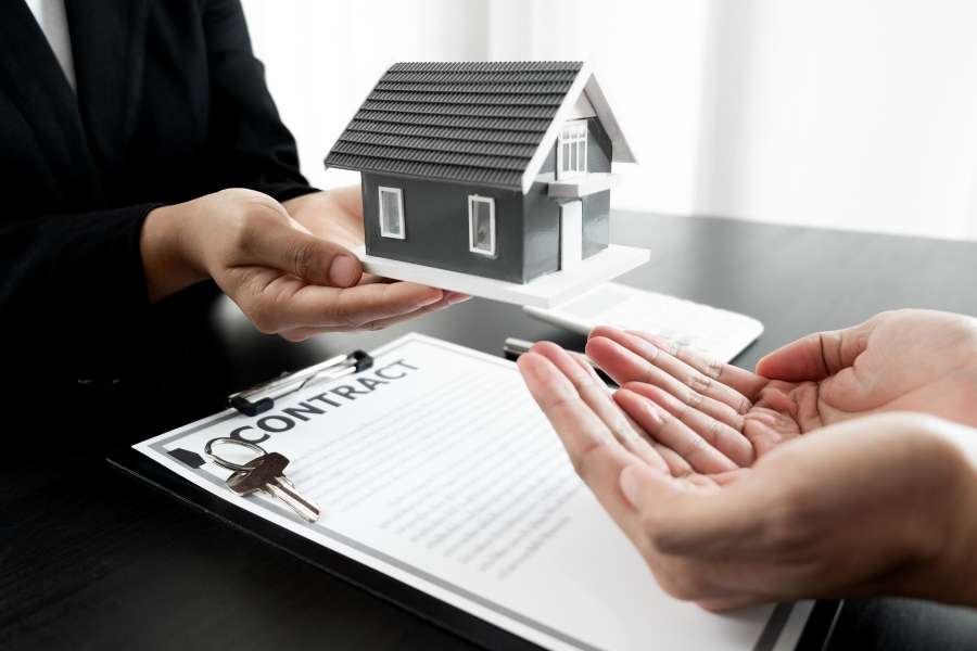 Professionnel remettant une maquette de maison lors de la négociation du loyer lors renouvellement bail