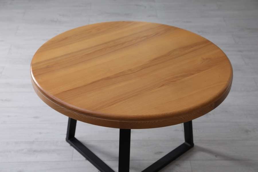 Une table basse design ronde avec un plateau en bois chaleureux et un piétement géométrique en métal noir.